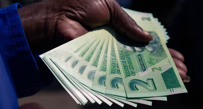 A man shows a wad of the new Zimbabwe two-dollar notes he received from a bank in Harare on November 12, 2019. Jekesai NJIKIZANA / AFP